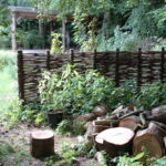 Opdeling med et vandret flettet pilehegn ind til naboen, og en fin opdeling af haven ved sommerhuset