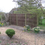 Det lodret flettede pilehegn flettet med pilesorten Kanelpil giver en dejlig og meget naturlig opdeling af haven