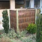 Afskærmning af affaldsspandene med et smukt pilehegn.