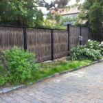 Smukt og harmonisk pile-hegn, flettet på sektioner af jernrammer med overliggere som beskytter pilen mod regnen.