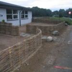 De to vandrette pilehegn omkranser legepladserne i en børnehave.