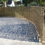 Harmonisk pilehegn som følger kanten på flisebelægningen.