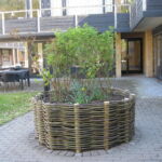 Flettede runddeller i pil til blomster og træer giver et dejlig miljø i omgivelserne.