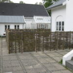 En hyggelige og funktionel indhegning med pilehegn omkring en terrasse i Ålsgårde.