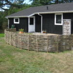 Lavt buet hegn indrammer den lille have til krukker.