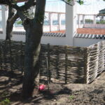 Tennisbanen omkranses af et lavt pilehegn så både indsigt og udsigt bevares.